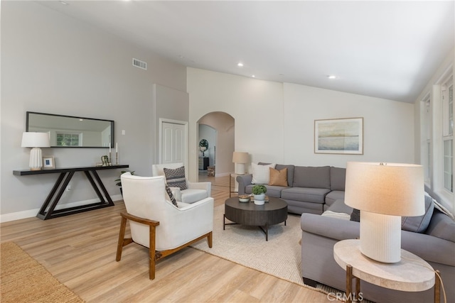 living area with visible vents, recessed lighting, arched walkways, light wood finished floors, and lofted ceiling