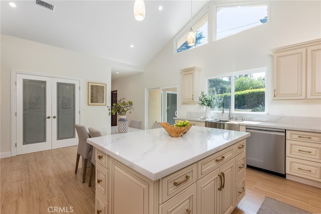 kitchen featuring stainless steel dishwasher, cream cabinetry, visible vents, and a sink