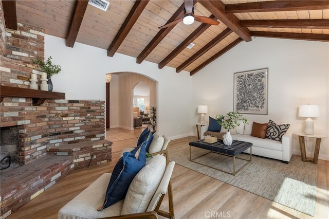 living area featuring light wood-style floors, beamed ceiling, visible vents, and arched walkways