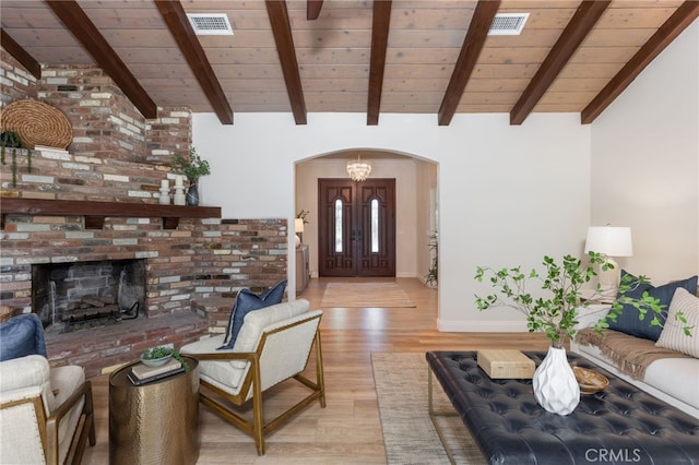 living room with visible vents, vaulted ceiling with beams, arched walkways, wood ceiling, and light wood-type flooring