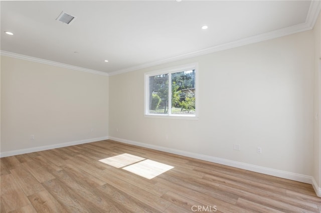 empty room with light wood-type flooring, visible vents, baseboards, and crown molding