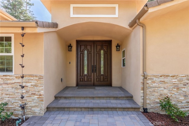 property entrance featuring stone siding and stucco siding