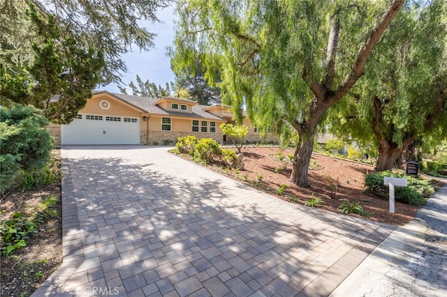 view of front of house with stone siding, stucco siding, an attached garage, and decorative driveway