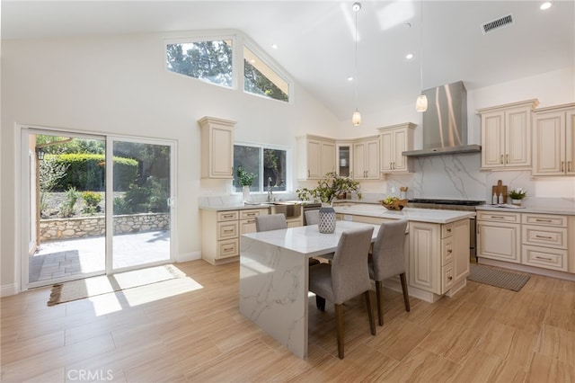 4 Singletree Ln, Rolling Hills Estates, CA 90274 - kitchen featuring wall chimney range hood, cream cabinetry, a center island, high vaulted ceiling, and a kitchen bar