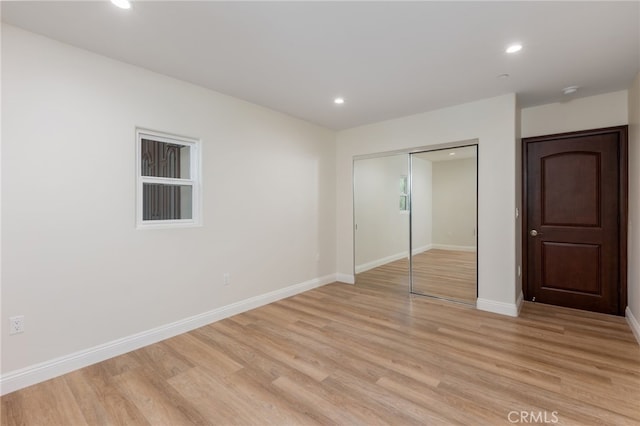 unfurnished bedroom featuring recessed lighting, light wood-style floors, baseboards, and a closet