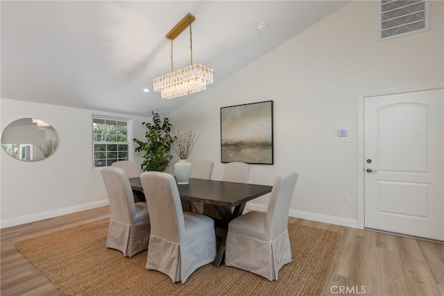 dining room featuring visible vents, baseboards, light wood-type flooring, and lofted ceiling