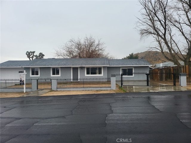 ranch-style home with a fenced front yard, a gate, and stucco siding