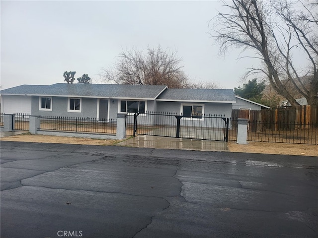 ranch-style house with a fenced front yard, a gate, and stucco siding