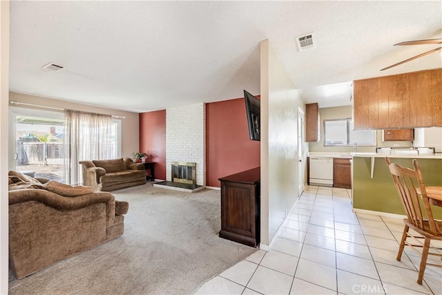 living room featuring light tile patterned floors, light carpet, visible vents, and a brick fireplace