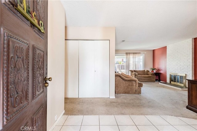 foyer featuring a brick fireplace, carpet flooring, and tile patterned floors