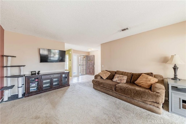 living area featuring carpet floors, visible vents, and a textured ceiling