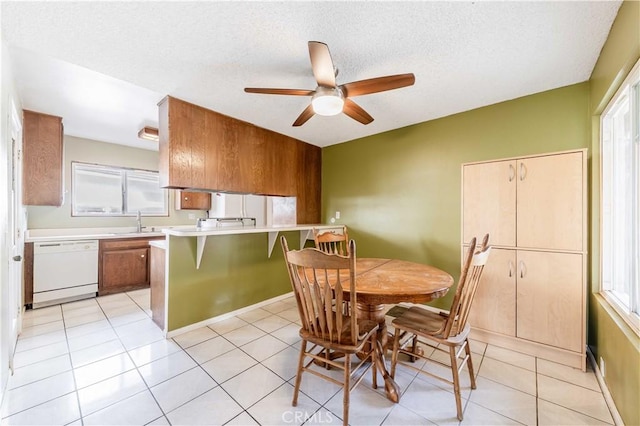 dining room with a ceiling fan, a healthy amount of sunlight, a textured ceiling, and light tile patterned floors