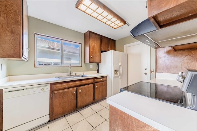 kitchen featuring brown cabinets, light countertops, a sink, ventilation hood, and white appliances