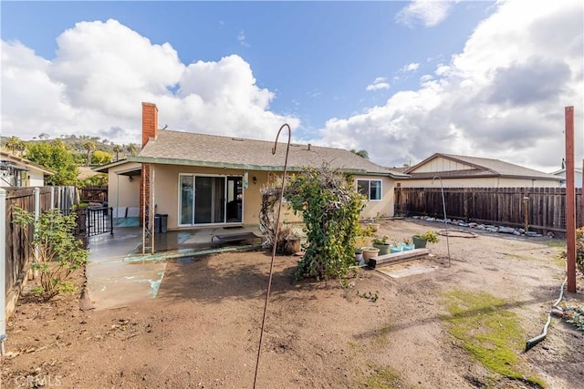 rear view of house featuring a vegetable garden, a fenced backyard, a chimney, a patio area, and stucco siding