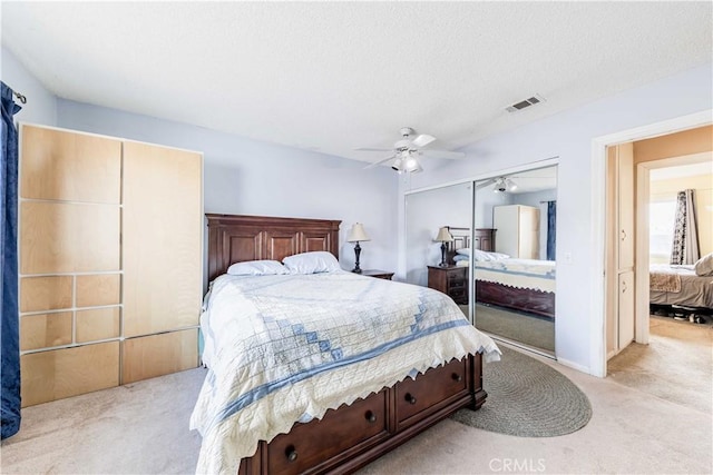 bedroom featuring a closet, light colored carpet, visible vents, a ceiling fan, and a textured ceiling