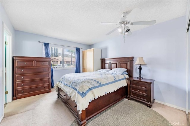 bedroom with ceiling fan, baseboards, a textured ceiling, and light colored carpet