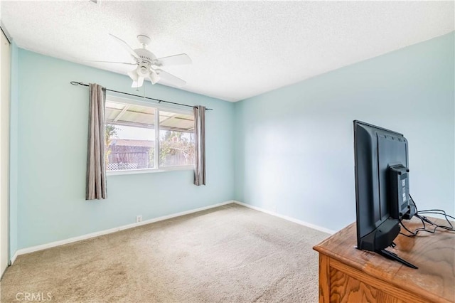 interior space with carpet floors, a textured ceiling, baseboards, and a ceiling fan