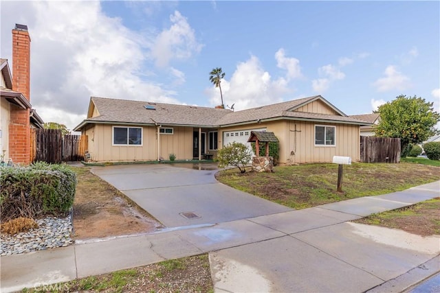 ranch-style home with board and batten siding, concrete driveway, fence, and an attached garage