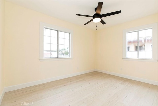 empty room featuring ceiling fan, baseboards, and wood finished floors