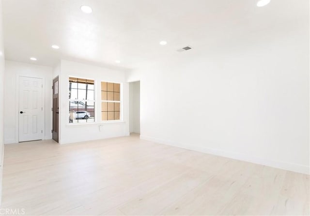 unfurnished room featuring baseboards, light wood-type flooring, visible vents, and recessed lighting