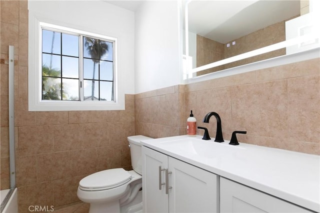 full bathroom featuring vanity, toilet, and tile walls