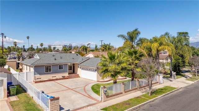 view of front of property featuring an attached garage, a fenced front yard, a gate, and concrete driveway