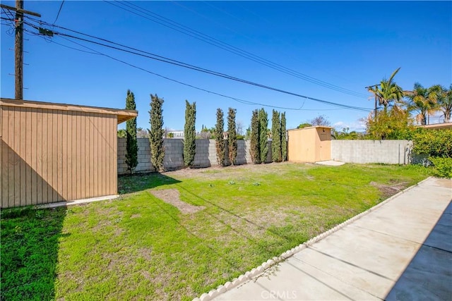 view of yard featuring a storage shed, a fenced backyard, and an outbuilding