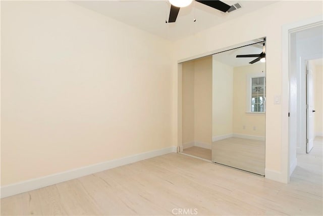 unfurnished room with a ceiling fan, visible vents, light wood-style flooring, and baseboards