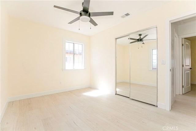 unfurnished bedroom with baseboards, visible vents, a ceiling fan, wood finished floors, and a closet