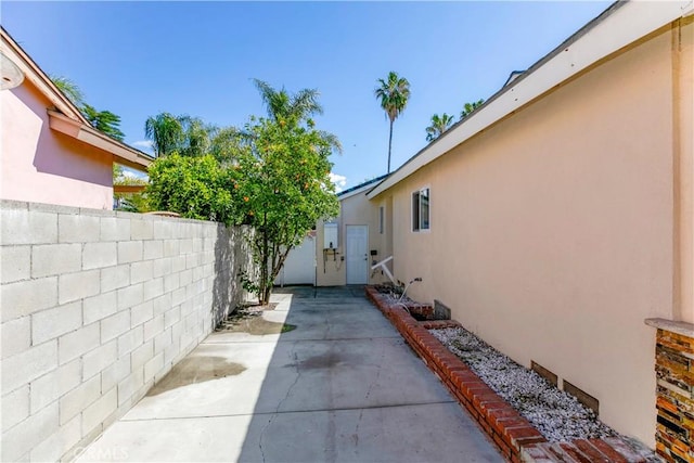 view of property exterior with a patio, fence, and stucco siding