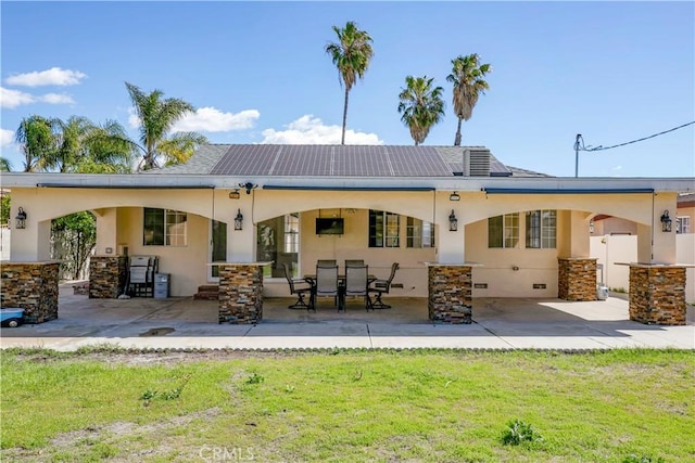 rear view of property featuring a patio, a lawn, and stucco siding