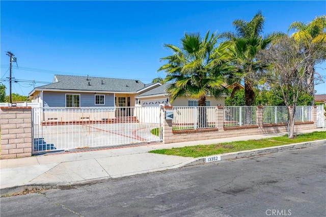 ranch-style home with driveway, a fenced front yard, an attached garage, and a gate