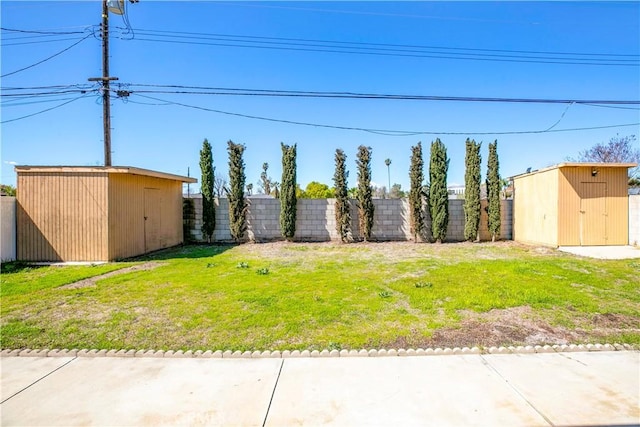 view of yard with a fenced backyard, a storage unit, and an outdoor structure