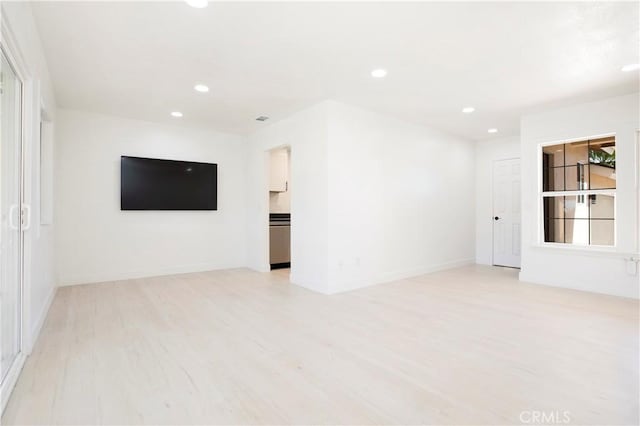 spare room with baseboards, light wood finished floors, and recessed lighting