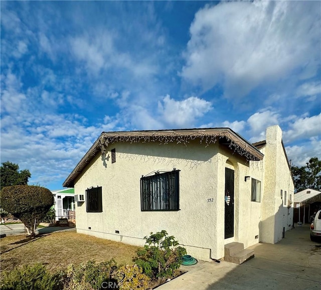 view of home's exterior with crawl space and stucco siding