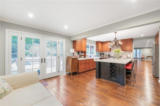 kitchen with brown cabinetry, dark wood finished floors, freestanding refrigerator, light countertops, and french doors