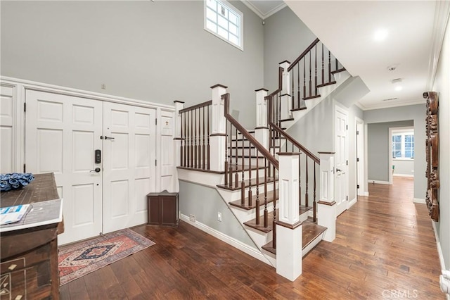 foyer featuring baseboards, crown molding, stairway, and hardwood / wood-style floors