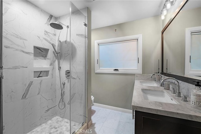 bathroom featuring toilet, marble finish floor, a marble finish shower, and a sink