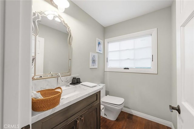 half bathroom featuring baseboards, vanity, toilet, and wood finished floors