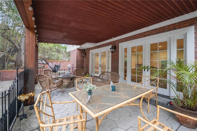 view of patio / terrace with outdoor dining space, a fire pit, and french doors