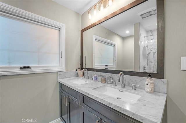 full bath featuring double vanity, a marble finish shower, a sink, and visible vents