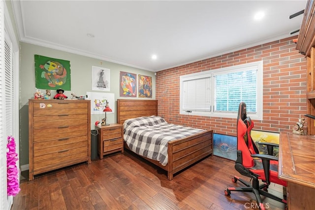 bedroom with dark wood-style floors, recessed lighting, ornamental molding, and brick wall