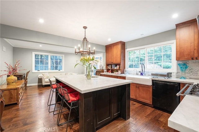 kitchen featuring dishwasher, dark wood-style floors, a kitchen island, a breakfast bar area, and a sink