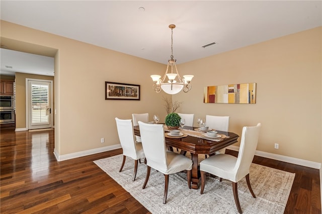 dining space with dark wood-type flooring, a notable chandelier, and baseboards