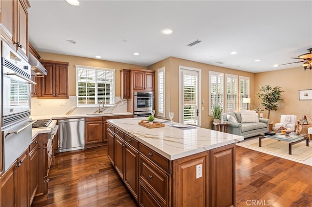 kitchen featuring stainless steel appliances, dark wood-type flooring, a sink, visible vents, and open floor plan