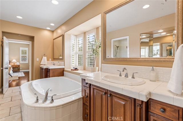 full bathroom featuring recessed lighting, a healthy amount of sunlight, a sink, and a bath