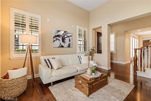 living room featuring baseboards, stairway, and wood finished floors