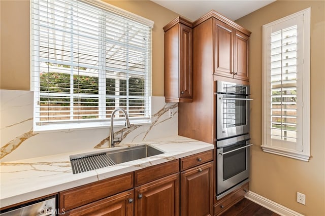 kitchen with brown cabinetry, backsplash, stainless steel appliances, and a sink