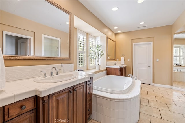 full bathroom with visible vents, two vanities, tile patterned floors, a sink, and a bath