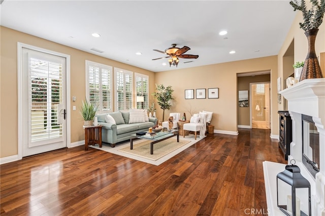 living area featuring dark wood-style floors, recessed lighting, baseboards, and a glass covered fireplace